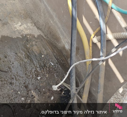 כבלים וצינורות על רצפה רטובה עם כתמי מים